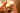 Der Fokus dieser Nahaufnahme liegt auf einer großen goldenen Weihnachtskugel, die auf der Brust eines kleinen Jungen liegt. Dieser wird über seine Schulter fotografiert, während er die Kugel mit einer Hand festhält. In deren glänzender Oberfläche spiegelt sich sein Gesicht.