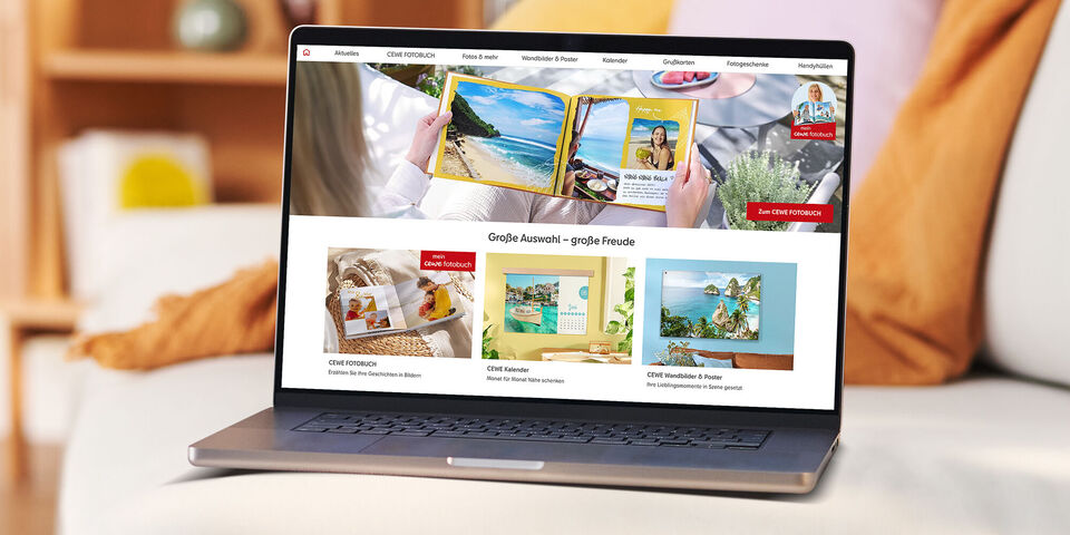 Laptop steht auf einer Couch und zeigt die Startseite der CEWE Fotowelt