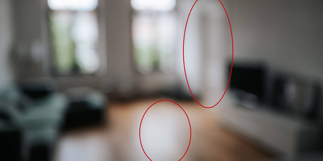 Es ist ein unscharfes Foto von einem Wohnzimmer zu sehen, auf dem in der Mitte und auf der rechten Seite ein roter Kreis eingezeichnet ist.